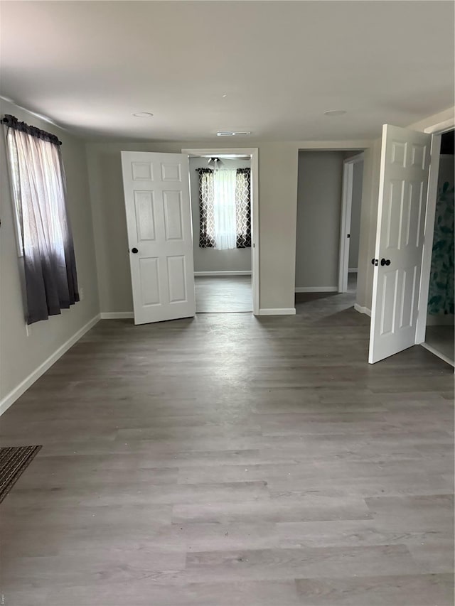 empty room featuring baseboards, visible vents, and wood finished floors