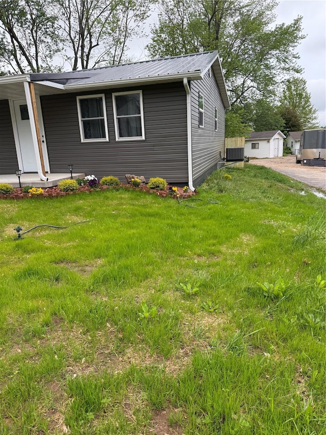 view of side of home featuring a lawn, covered porch, and metal roof
