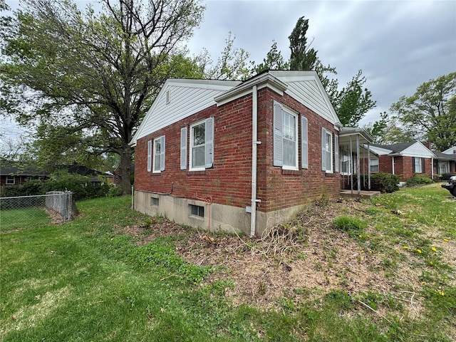 view of home's exterior featuring fence, a lawn, and brick siding