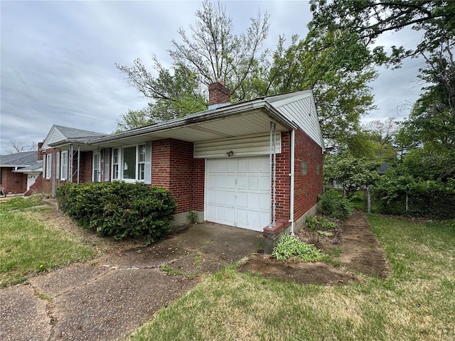 view of side of property with a garage, a chimney, brick siding, a lawn, and driveway