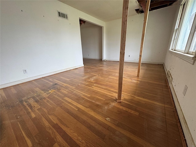 empty room with baseboards, visible vents, and wood finished floors