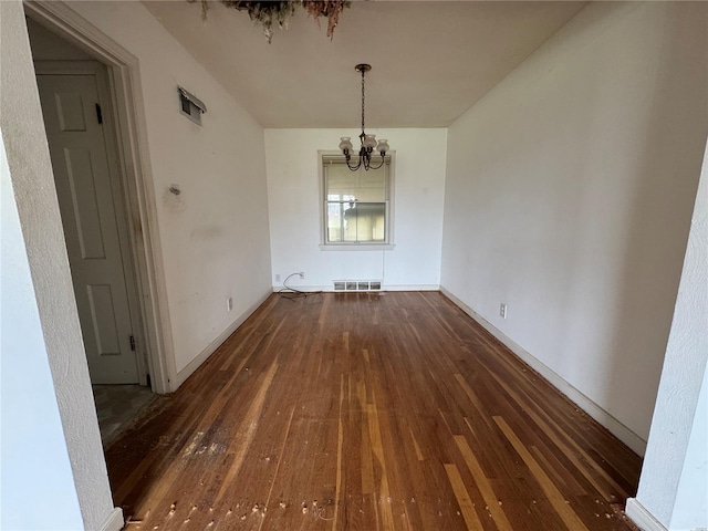 unfurnished dining area featuring baseboards, a chandelier, hardwood / wood-style floors, and visible vents