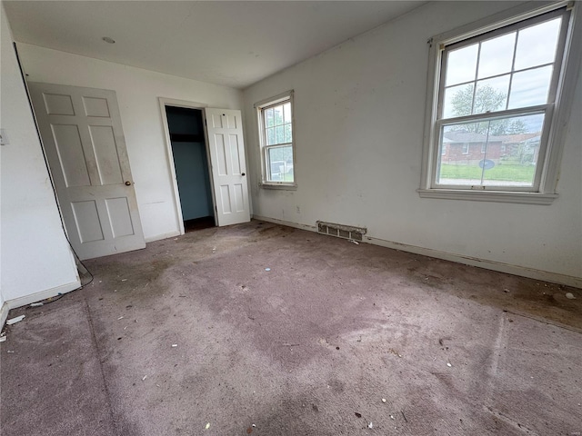 unfurnished bedroom featuring baseboards, visible vents, multiple windows, and a closet