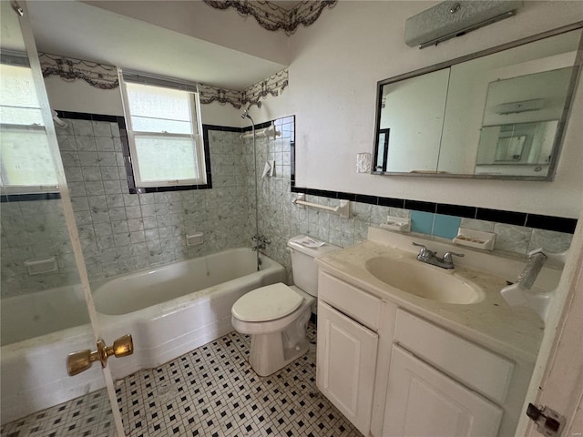 bathroom featuring vanity, bathtub / shower combination, toilet, a wainscoted wall, and tile walls