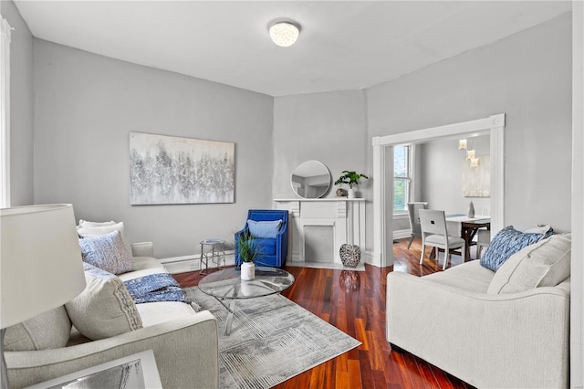 living room featuring a fireplace with flush hearth, baseboards, and wood finished floors