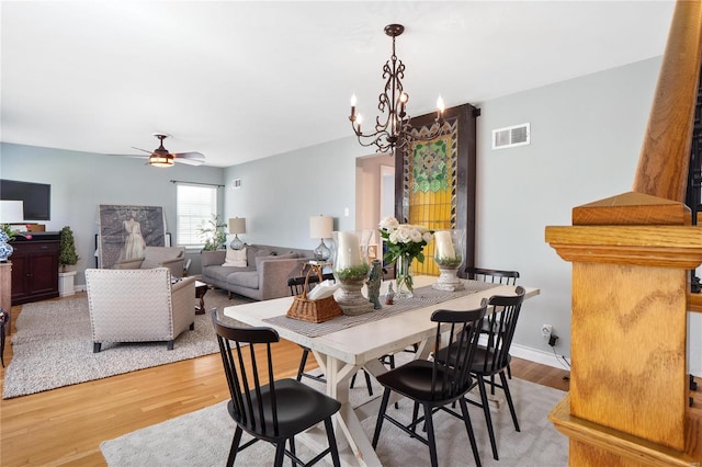 dining area with ceiling fan with notable chandelier, wood finished floors, and visible vents