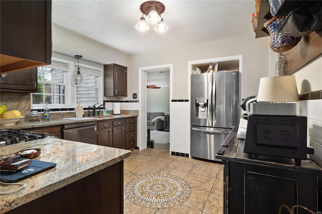 kitchen featuring dark brown cabinetry, stainless steel refrigerator with ice dispenser, light stone countertops, dishwasher, and light tile patterned floors