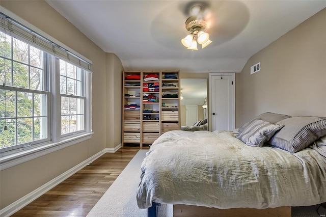 bedroom featuring visible vents, a closet, wood finished floors, baseboards, and a ceiling fan