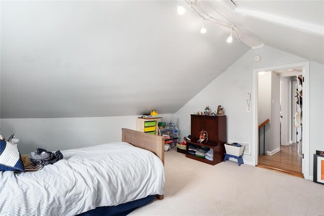 bedroom featuring track lighting, carpet flooring, and lofted ceiling