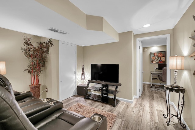 living area with baseboards, light wood-style flooring, and visible vents