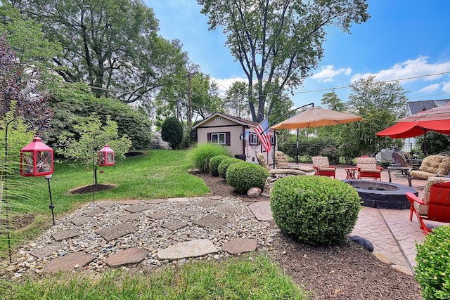 view of yard featuring a fire pit, a patio area, and an outbuilding