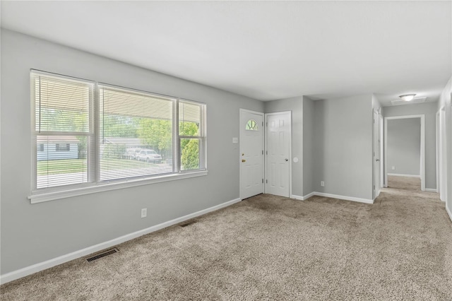 empty room with carpet flooring, baseboards, and visible vents