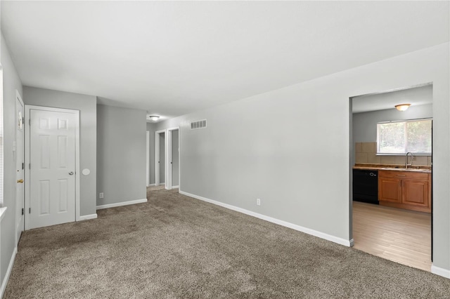 interior space featuring a sink, baseboards, light colored carpet, and visible vents