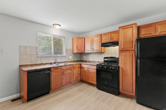 kitchen with backsplash, light wood-type flooring, a sink, black appliances, and under cabinet range hood