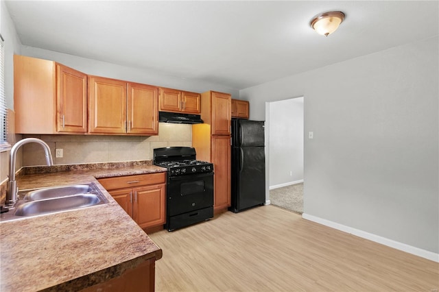 kitchen featuring extractor fan, light wood-type flooring, tasteful backsplash, a sink, and black appliances