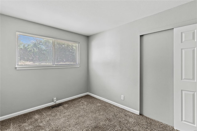 unfurnished bedroom featuring carpet floors, baseboards, visible vents, and a closet