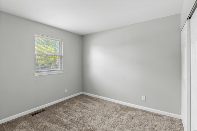 carpeted spare room featuring baseboards and visible vents