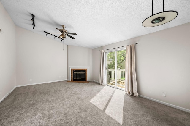 unfurnished living room with carpet floors, ceiling fan, a textured ceiling, and a tile fireplace
