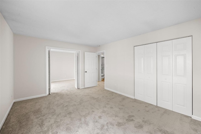 unfurnished bedroom with a closet, baseboards, and carpet flooring