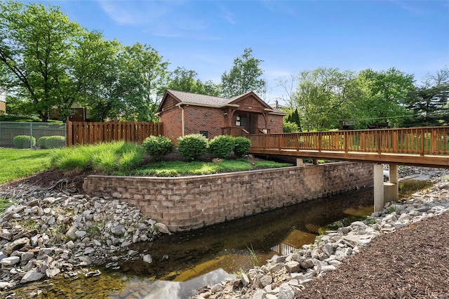 view of side of home with brick siding, fence, and a deck