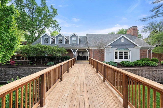 rear view of property with brick siding, a chimney, and a shingled roof