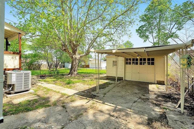 detached garage with fence, central AC, and driveway