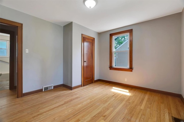 spare room featuring baseboards, light wood-style flooring, and visible vents
