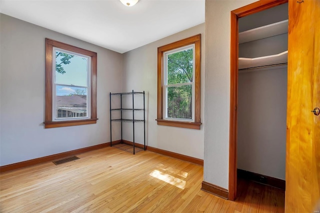 unfurnished bedroom featuring visible vents, light wood-style floors, baseboards, and multiple windows