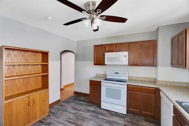kitchen with white appliances, arched walkways, light countertops, dark wood finished floors, and a ceiling fan