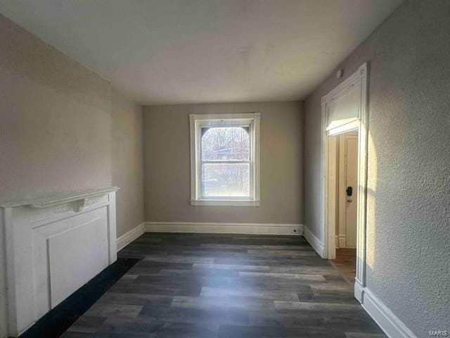 interior space with baseboards, dark wood finished floors, and a textured wall