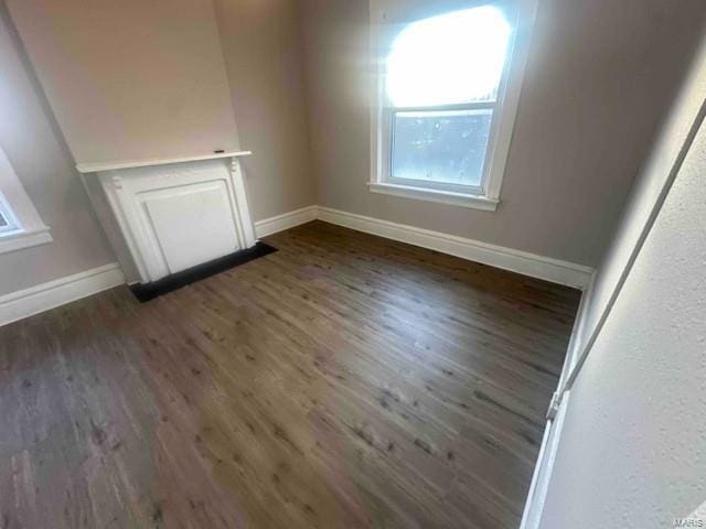 spare room featuring baseboards and dark wood-style floors