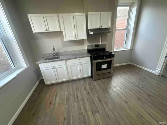 kitchen with stainless steel range with gas stovetop, baseboards, under cabinet range hood, and white cabinetry