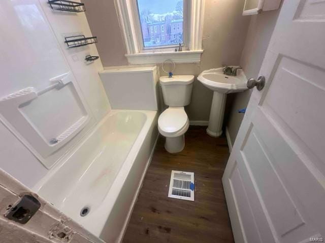 full bathroom with visible vents, wood finished floors, baseboards, a bathing tub, and toilet