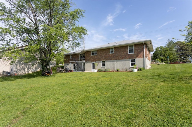 rear view of property with a lawn and brick siding