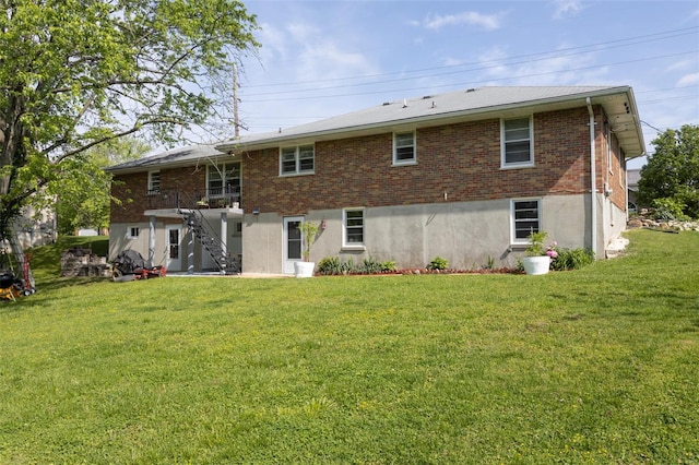 back of property with a lawn, stairway, and brick siding