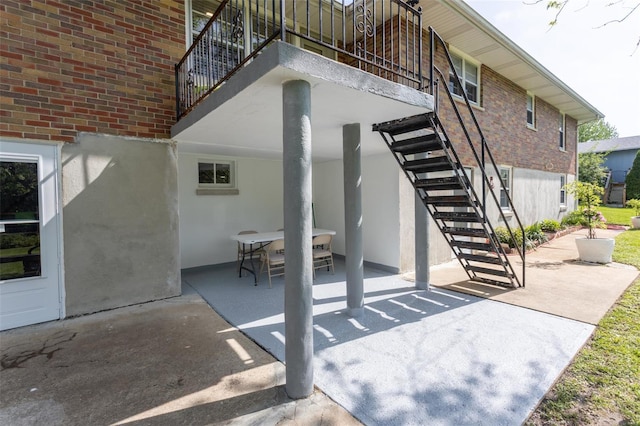 view of patio with stairway, outdoor dining space, and a balcony
