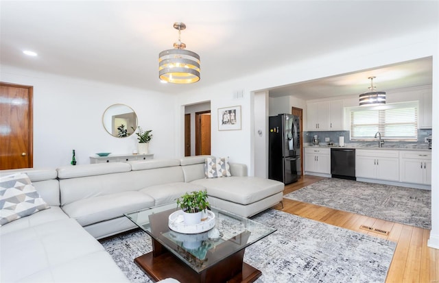 living area featuring visible vents, light wood finished floors, and a notable chandelier