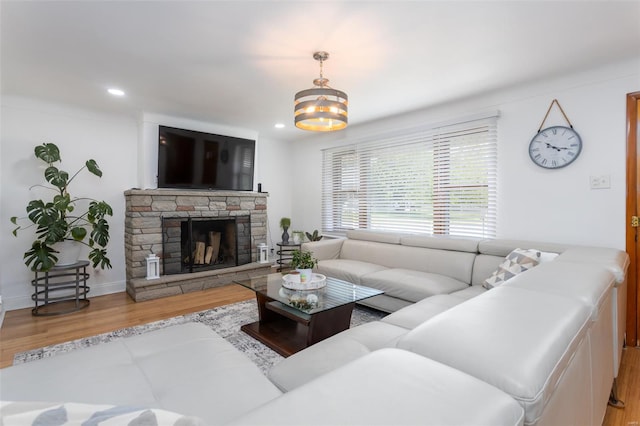 living area with recessed lighting, a chandelier, a stone fireplace, and wood finished floors