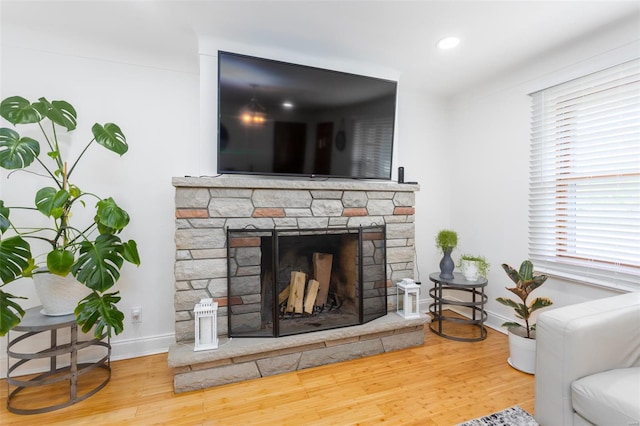 living area featuring recessed lighting, baseboards, a stone fireplace, and wood finished floors