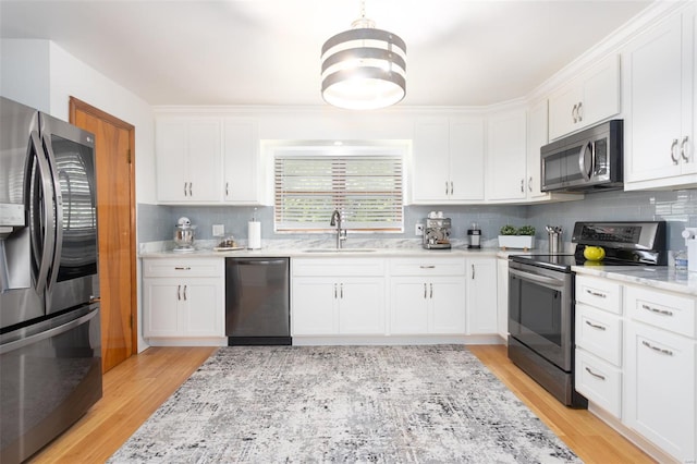 kitchen with a sink, white cabinetry, tasteful backsplash, and stainless steel appliances