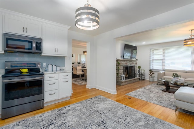 kitchen featuring an inviting chandelier, open floor plan, white cabinetry, backsplash, and stainless steel appliances