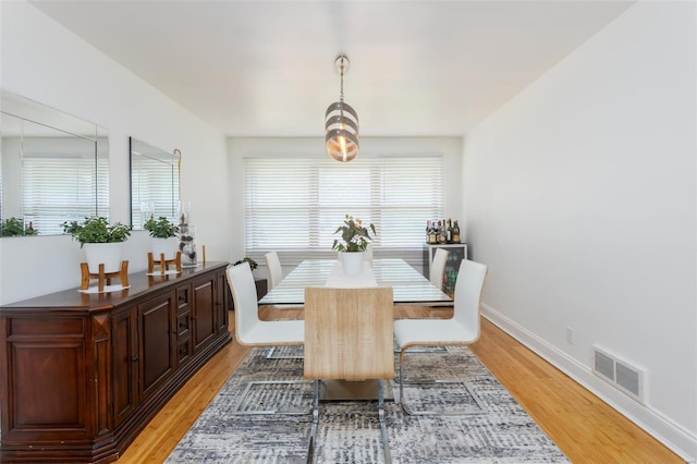 dining area featuring light wood-style floors, baseboards, and visible vents