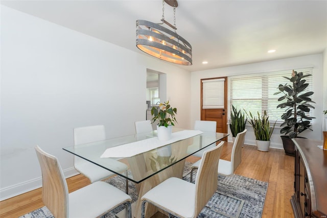 dining room with baseboards, plenty of natural light, light wood-style flooring, and a notable chandelier