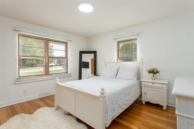 bedroom featuring baseboards, multiple windows, light wood-style flooring, and visible vents