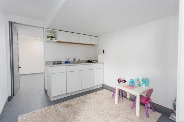 interior space featuring white cabinets, open shelves, a sink, light countertops, and baseboards