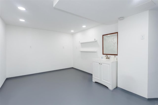 spare room featuring recessed lighting, a sink, concrete floors, and baseboards