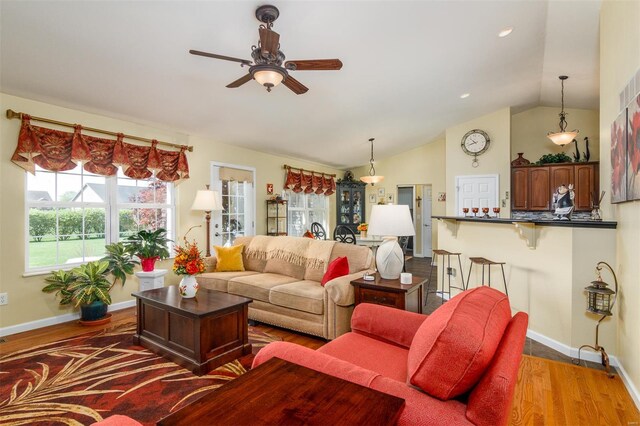 living room with baseboards, ceiling fan, vaulted ceiling, and wood finished floors