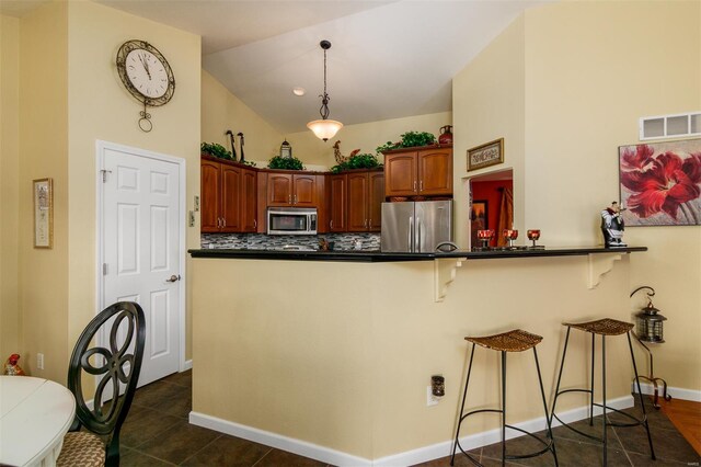 kitchen with lofted ceiling, a breakfast bar, dark countertops, tasteful backsplash, and stainless steel appliances