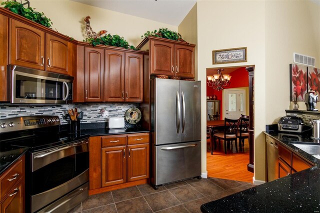 kitchen with visible vents, appliances with stainless steel finishes, tasteful backsplash, dark tile patterned flooring, and a chandelier