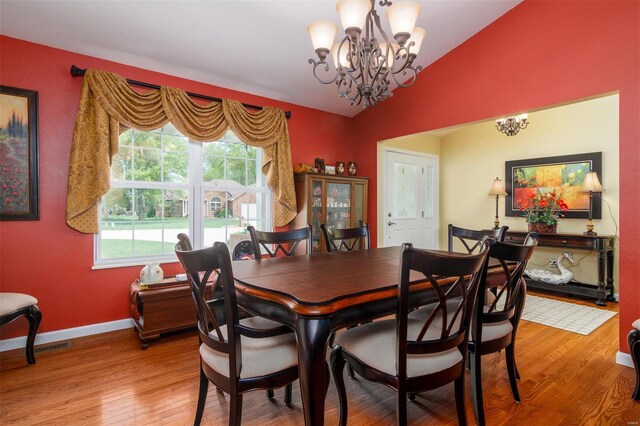 dining room featuring baseboards, vaulted ceiling, an inviting chandelier, and light wood-style floors